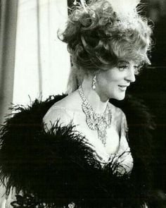 an old black and white photo of a woman in a feathered dress with her hair pulled back