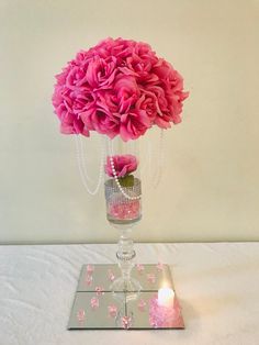 a vase filled with pink flowers sitting on top of a table next to a candle