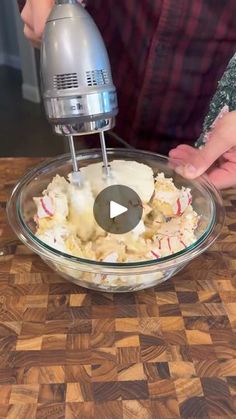 a person mixing food in a bowl with a mixer on the table next to it