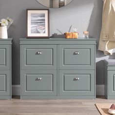 a grey dresser with two drawers and a mirror on the wall next to it in a room