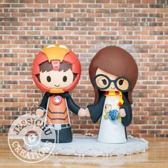 a wedding cake topper with a bride and groom holding hands in front of a brick wall