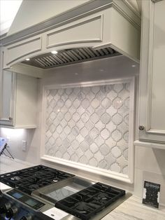 a stove top oven sitting inside of a kitchen next to white cabinets and counter tops