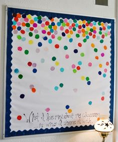 a bulletin board with colorful confetti on it and a lamp next to it