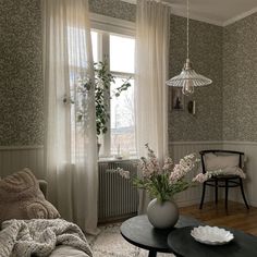 a living room filled with furniture next to a window covered in white drapes and curtains