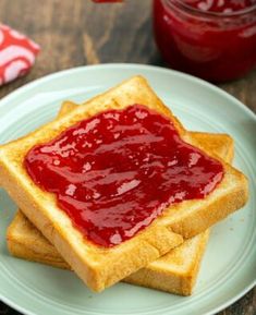 two pieces of toast with ketchup on them sitting on a plate next to a jar of jelly