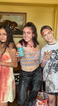 three girls are posing for the camera with paint all over their face and body, while one girl is holding a can