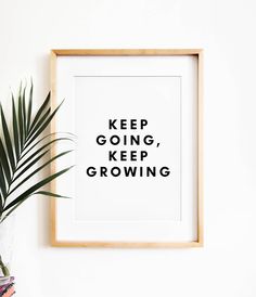 a framed poster with the words keep going, keep growing in black on it next to a potted plant