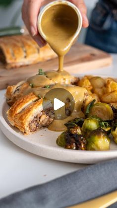 someone is pouring sauce on some food that includes brussel sprouts and potatoes