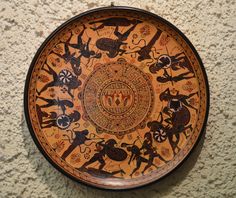 a decorative plate on the wall with animals and people painted on it's surface