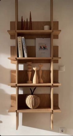 a wooden shelf with vases, books and other items on it in a living room