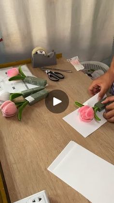 someone making flowers out of paper on a table