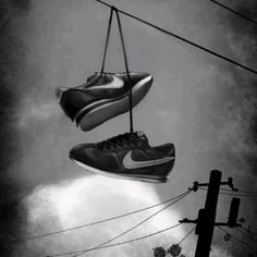 two pairs of shoes hanging from wires in the air with clouds and sun behind them