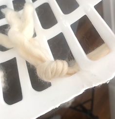 a piece of white yarn sitting on top of a plastic container with holes in it