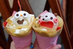 two ice cream cones with faces and noses on them are being held by someone's hand