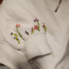 a white sweatshirt with embroidered flowers on it