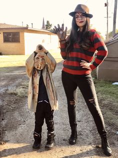 two people dressed up in costumes standing on a dirt road with their hands out to the side