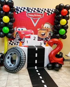 a birthday party with balloons and cars on the floor, including an entrance to a race track