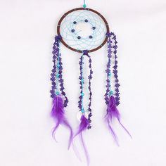 a purple and white dream catcher hanging on a wall