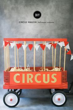 an orange wagon with sticks in it and some flags on the top is advertising circus