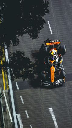 an orange race car driving down the street