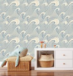 a blue and white wallpaper with waves on it in a living room next to a basket