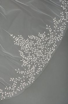 a veil with white flowers and leaves on the top is shown in front of a gray background