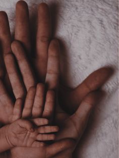 a group of hands that are on top of a white blanket with one hand extended up to the other