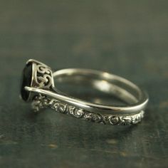 a silver ring with a black stone on it's side and filigrees around the band