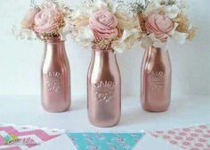 three pink vases with flowers in them on a white tableclothed cloth next to each other