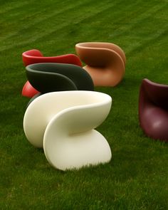 several different colored chairs sitting in the grass