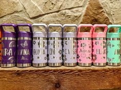 a row of colorful canisters sitting on top of a wooden shelf next to a stone wall