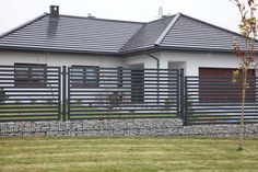 a house with a fence in front of it and grass on the ground next to it