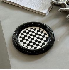 a black and white checkered plate sitting on top of a table next to an open book