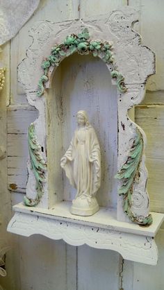 a statue of jesus is sitting on a shelf in front of a white painted wall