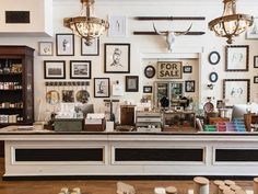 a store front with lots of framed pictures on the wall and below it is a cash register