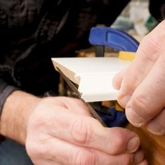 a man is using a pair of scissors to cut something out of paper on a piece of wood