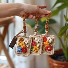 two small crocheted keychains with flowers on them are being held by a hand