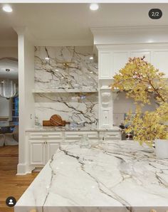 a kitchen with marble counter tops and white cabinets, along with a vase filled with flowers