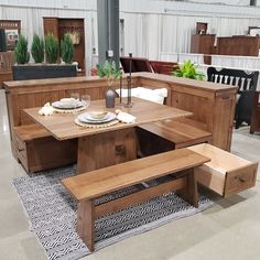 a table and benches in a room with wooden furniture on the floor at an indoor showroom