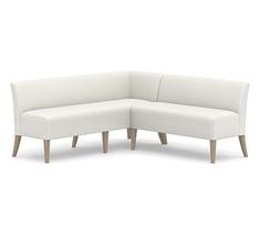 a white sectional couch with wooden legs