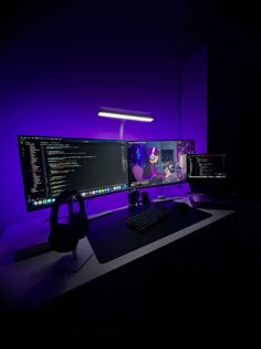 two computer monitors sitting next to each other on top of a desk in the dark