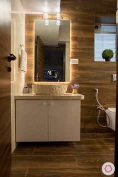 a bathroom with a sink, toilet and mirror on the wall next to each other