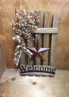 a welcome sign with a star on it next to a wooden fence and some flowers