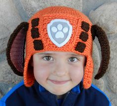 a young boy wearing an orange crocheted hat with a paw print on it