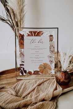 the wedding menu is displayed on a wooden tray with dried flowers and pamy leaves