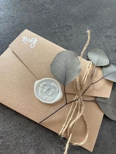 a close up of an envelope with a wax stamp on it and some leaves tied to the front