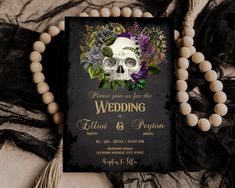 a wedding card with a skull and flowers on the front, surrounded by wooden beads