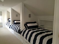 two beds in a room with black and white striped sheets on them, under the slanted roof