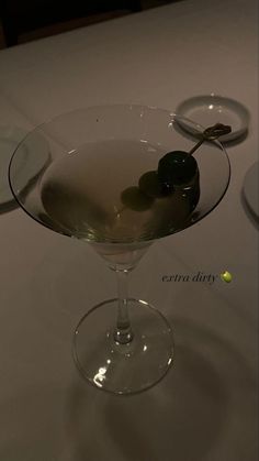 a martini glass with olives in it on a table