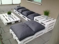 some white pallets sitting on top of a roof next to plants and potted plants